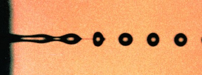 fotografía bajo microscopio de un chorro de líquido, que se rompe formando gotas debido a la tensión superficial